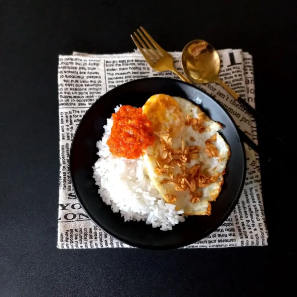 Siapkan nasi, tata ceplok telur bawang putih dan beri sambal sebagai pelengkap.