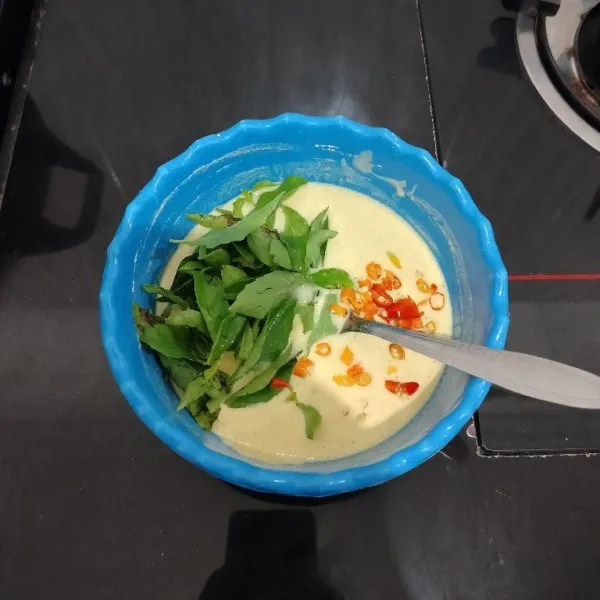 Lalu masukkan daun kemangi dan cabai rawit, kemudian aduk rata kembali.