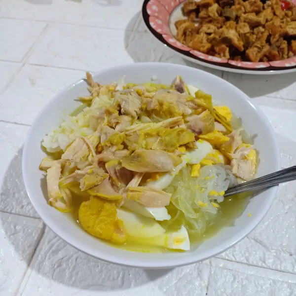 Sajikan soto dengan ayam yang disuir-suir dan pelengkapnya.