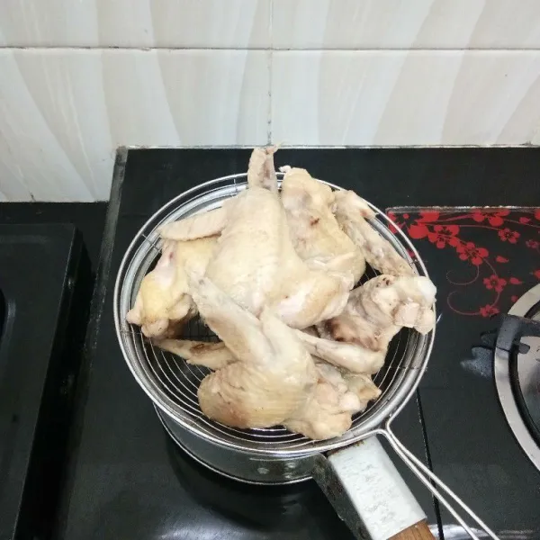 Kemudian tiriskan ayam dan buang air rebusannya.