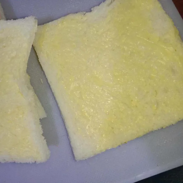 Oles 1 sisi roti tawar dengan mentega, makin banyak mentega makin gurih.