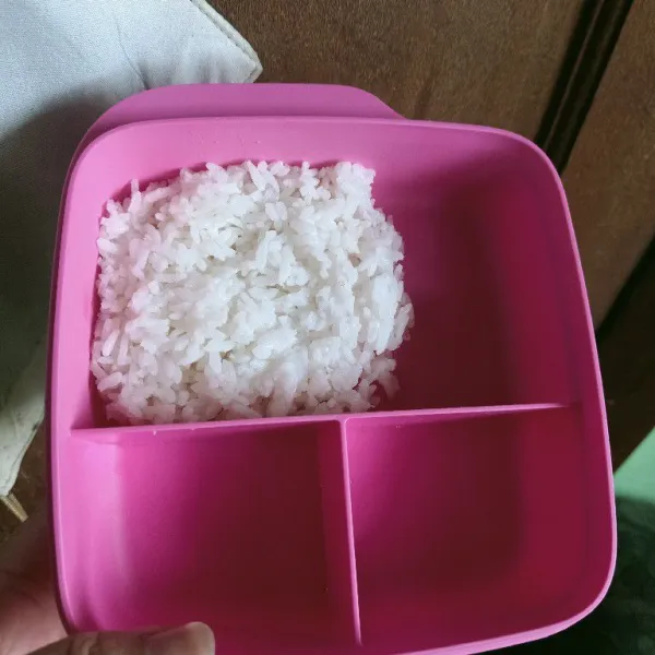 Siapkan nasi putih matang, masukkan ke dalam wadah bekal.