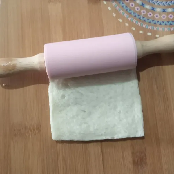 Ambil 1 lembar roti tawar lalu pipihkan dengan bantuan rolling pin, lakukan hal yang sama dengan sisa roti tawarnya, sisihkan.