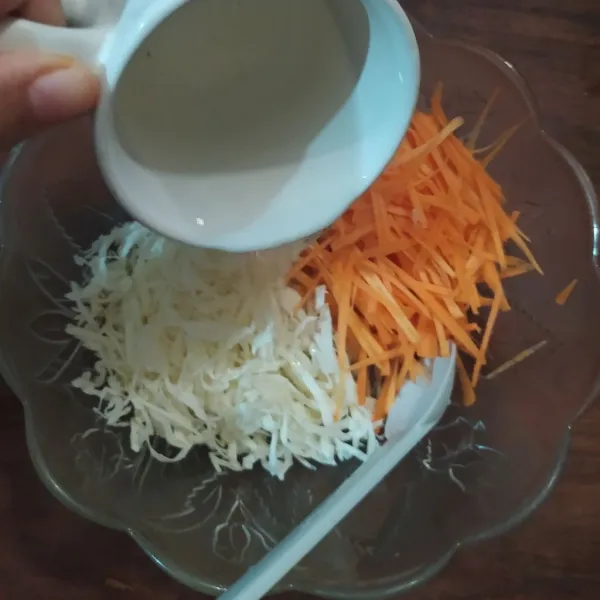 Tuang larutan gula, cuka beras dan sisa air  ke dalam mangkuk berisi irisan wortel dan kol.