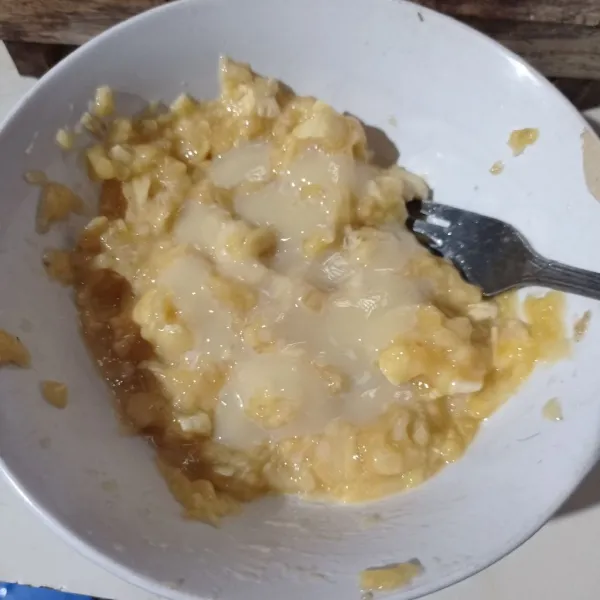 Lumatkan pisang, beri kental manis putih, aduk rata.