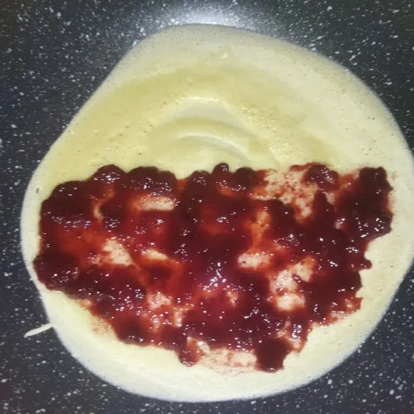 Lalu tuang kembali adonan, biarkan hingga adonan berlubang dan matang, beri selai strawberry secukupnya, jika bagian bawahnya sudah coklat dan matang, lipat lalu angkat.