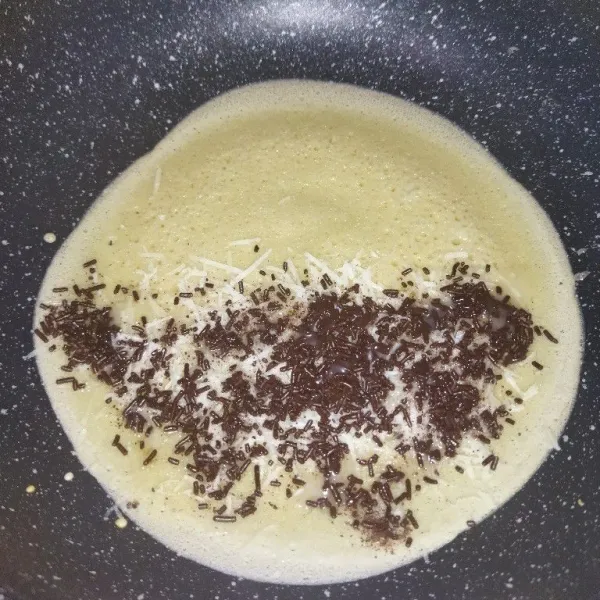 Diamkan hingga adonan atas belubang dan mulai matang, lalu taburi keju cheddar parut, meses dan krimer kental manis.