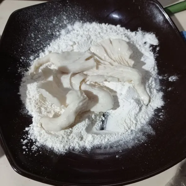 Campur bahan pelapis kering jadi satu, lalu gulingkan jamur sampai tertutup tepung.