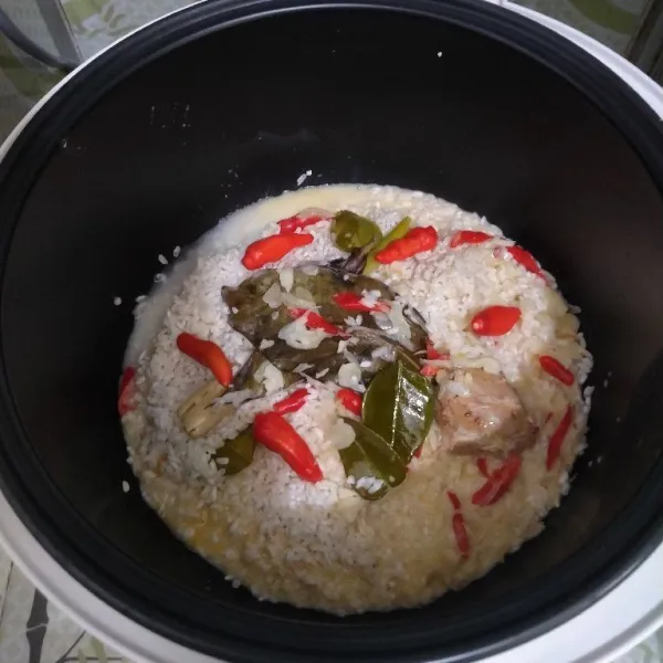 Masukkan bumbu tumis beserta santan tadi ke dalam rice cooker yang sudah terisi beras.
