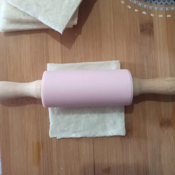 Pipihkan roti tawar dengan bantuan rolling pin.