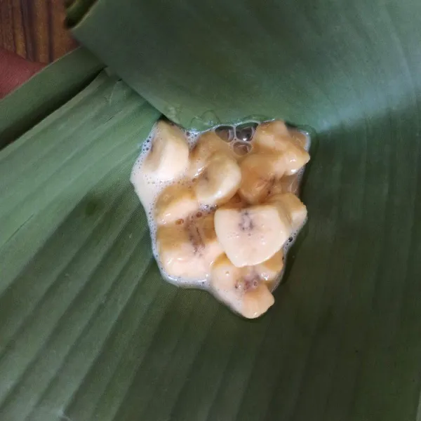 Ambil 2 lembar daun pisang, tumpuk menjadi satu kemudian tambahkan adonan carang gesing secukupnya.