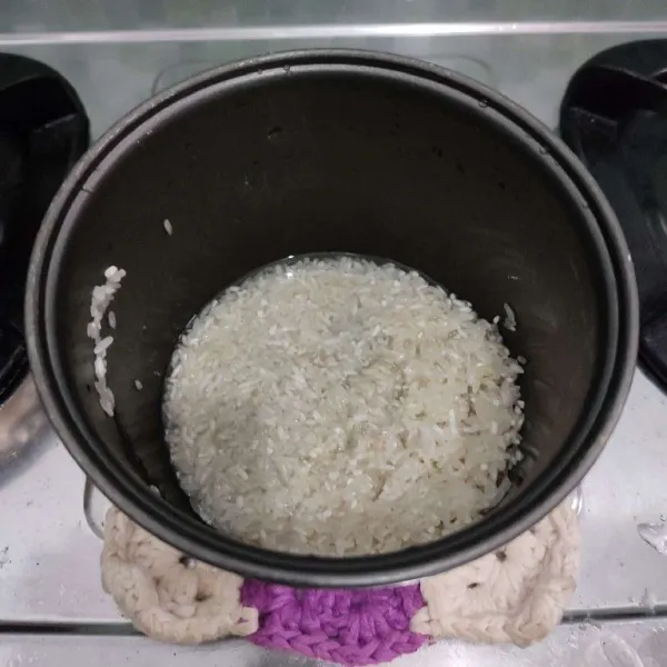 Cuci bersih beras kemudian pindahkan ke dalam panci rice cooker.