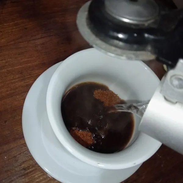 Lalu tuang air panas ke dalam cangkir kopi dan gula.
