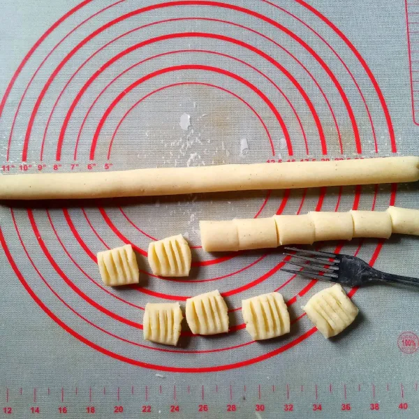 Bagi adonan menjadi dua bagian. Buat silinder panjang sambil dipadatkan. Potong-potong sepanjang satu ruas jari. Kemudian tekan permukaannya dengan garpu.