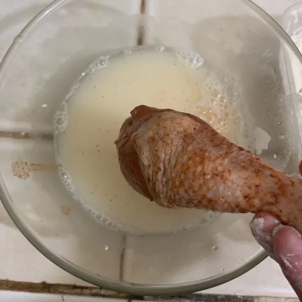 Siapkan adonan tepung basah dan kering. Adonan basah campurkan 100 ml air dengan 2 sdm tepung bumbu ayam goreng. Ambil ayam lalu celupkan ke dalam adonan tepung basah.