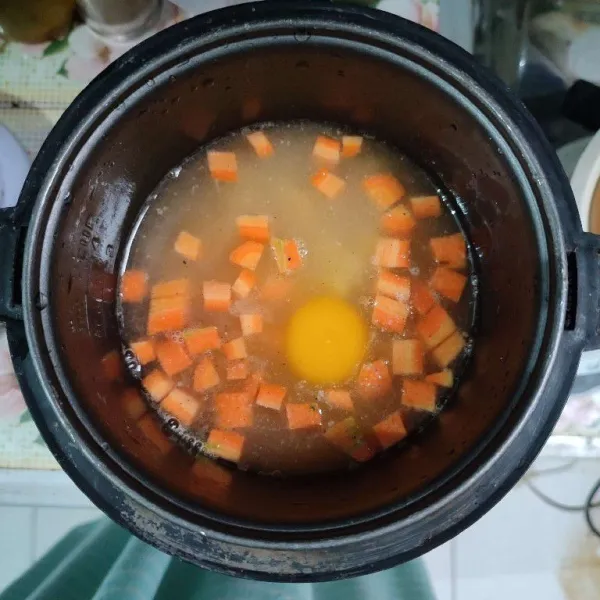 Masukkan telur, kemudian pindahkan ke dalam rice cooker. Masak nasi hingga matang.