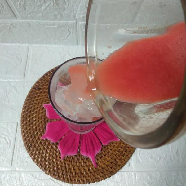 Tiang smoothies semangka ke dalam gelas saji.