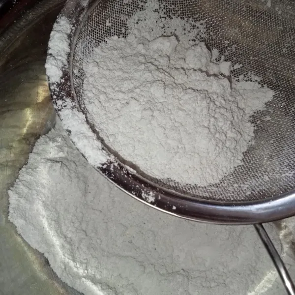 Perciki tepung beras dengan 30 ml air pasta pandan dan masukkan garam, uleni hingga rata (tidak Kalis) lalu saring tepung.