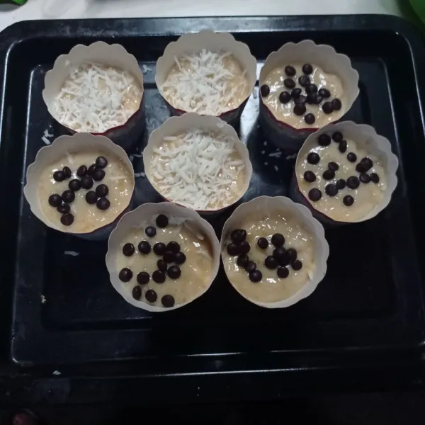Siapkan cup muffin, lalu masukan 3 sdm adonan, beri toping keju parut dan chocochips.
