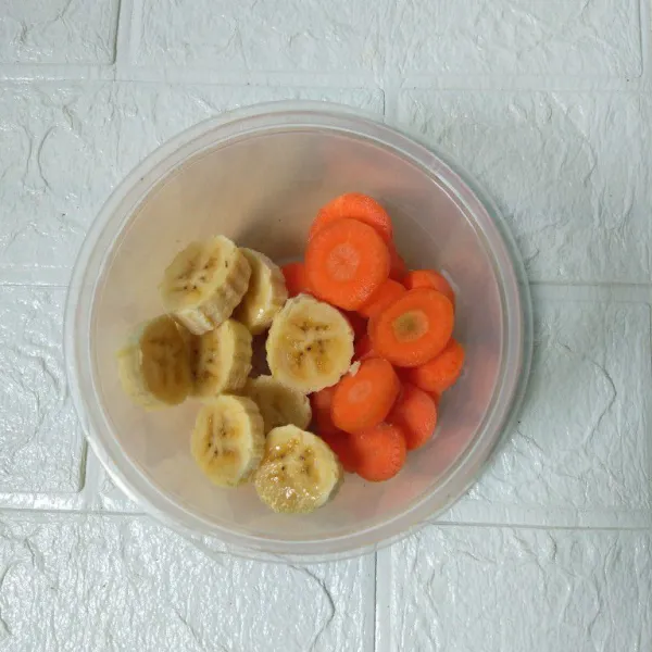 Kupas pisang dan wortel lalu potong-potong.