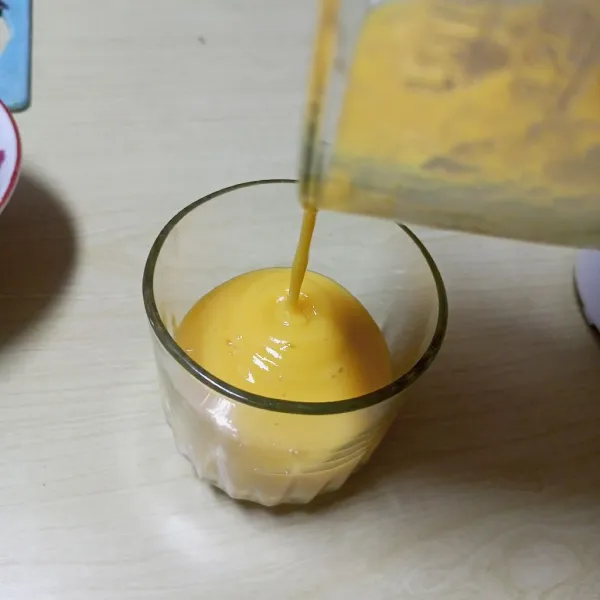 Tuang smoothies di dalam gelas saji. Beri potongan mangga dan chia seed.