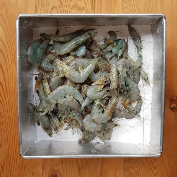 Setelah 15 menit, ambil secukupnya udang yang sudah dimarinasi, kemudian masukkan ke dalam wadah berisi campuran tepung. Aduk hingga semua bagian udang terbalut tepung. Angkat udang dengan bantuan sarigan, goyang-goyang saringan agar tidak terlalu banyak tepung saat menggoreng nanti.