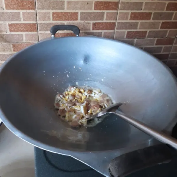 Goreng telur dengan minyak dan orak arik. Masukkan sosis dan bawang putih, masak hingga harum.