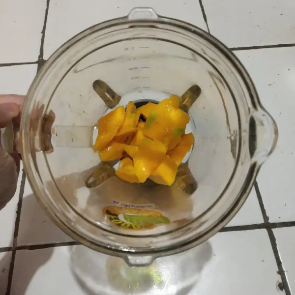 Masukkan potongan mangga, madu dan susu ke dalam blender, haluskan.