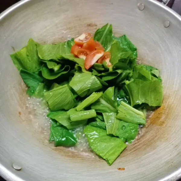 Kemudian masukkan daun caisim dan tomat, aduk rata.