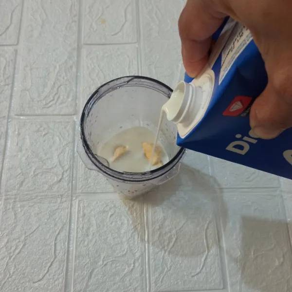 Masukkan potongan pisang ke dalam blender, lalu tuang susu cair.