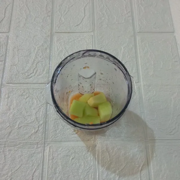 Masukkan potongan melon dan air jeruk ke dalam blender.