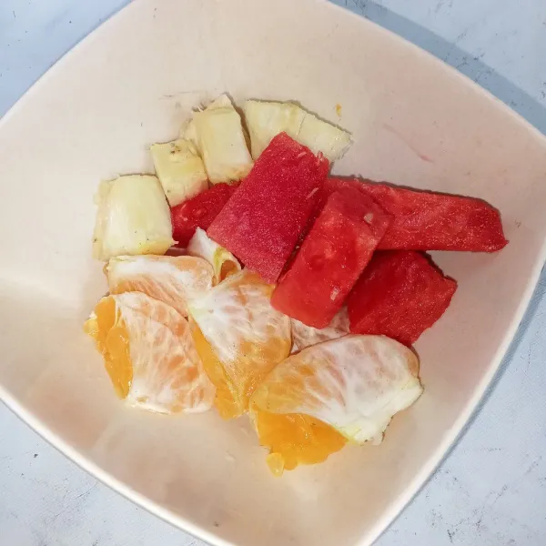 Buang biji jeruk, potong-potong nanas dan semangka.