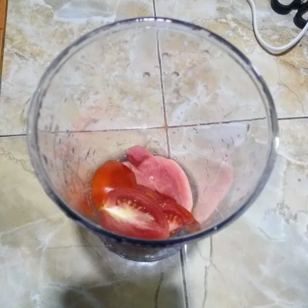 Masukkan tomat dan jambu merah ke dalam gelas blender.