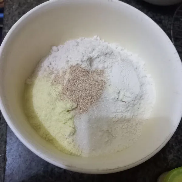 Dalam wadah campur tepung terigu, gula pasir, susu bubuk, ragi instan dan susu cair, uleni hingga rata.