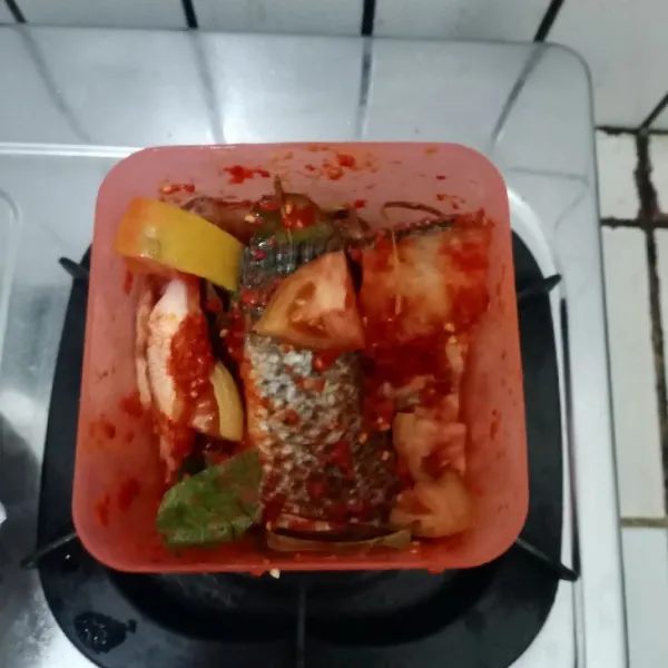 Baluri ikan dengan bumbu halus. Masukkan tomat, daun jeruk, daun salam, serai dan daun kunyit. Aduk rata, diamkan 30 menit agar bumbu meresap.