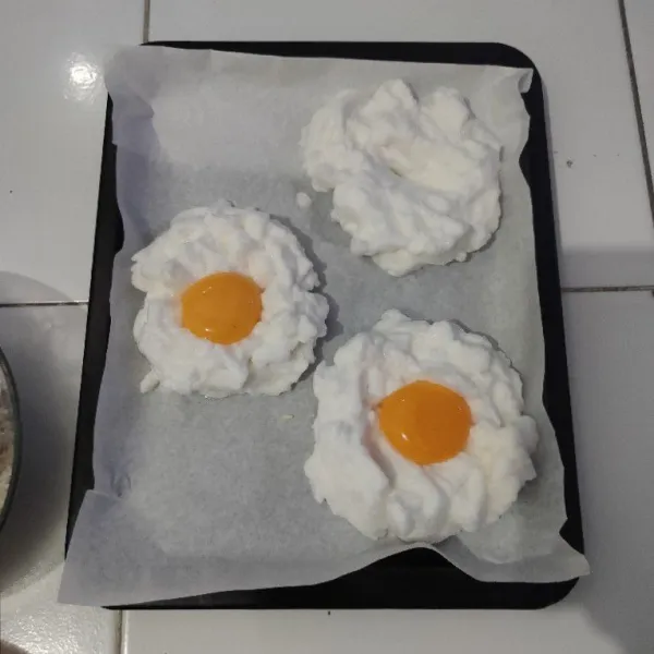 Buat cekungan pada bagian tengah putih telur lalu letakkan kuning telur ditengahnya.