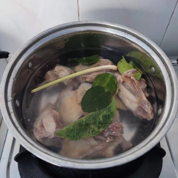 Rebus ayam bersama daun salam, daun jeruk purut, serai dan 800 ml air sampai empuk.