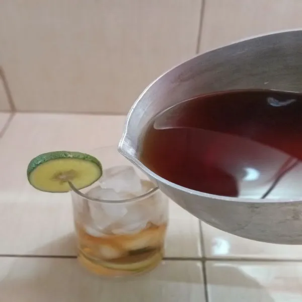 Tuang air teh yang sudah dingin ke dalam gelas dan siap untuk dinikmati.