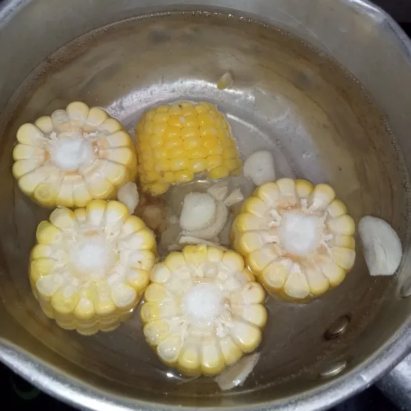 Rebus air hingga mendidih lalu masukkan bawang putih yang sudah dirajang dan temu kunci yang sudah digeprek aduk rata. Masukkan jagung, masak jagung hingga mulai matang.