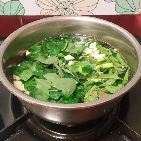 Kemudian masukkan daun kelor, daun bawang, dan daun kemangi, lalu aduk rata.