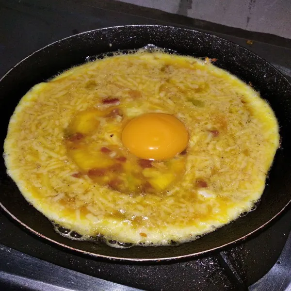 Lubangi bagian tengah dengan spatula, lalu ceplok 1 butir telur.