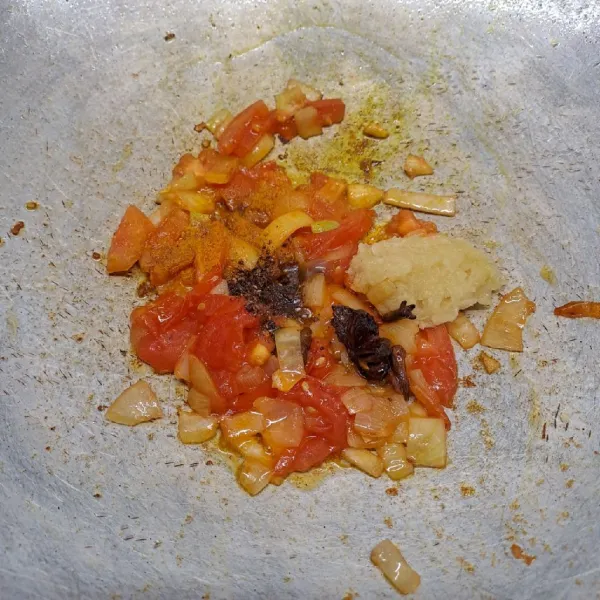 Masukkan irisan tomat, garam masala, dan bubuk kunyit. Aduk sampai rata dan tomat layu.