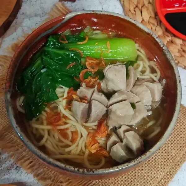 Tata mie dan sawi dalam mangkuk lalu tambahkan bakso dan siram dengan kuahnya. Sajikan bersama pelengkap.