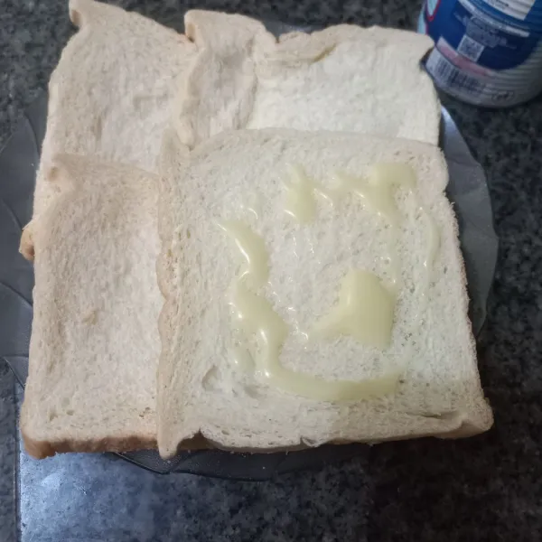 Siapkan roti tawar, olesi 2 lembar roti dengan kental manis, ratakan