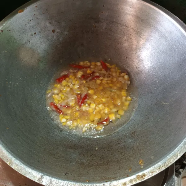 Lalu panaskan minyak. Tumis bawang putih dan cabe sampai harum. Lalu masukkan jagung dan air. Biarkan sampai mendidih.