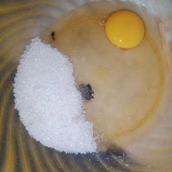 Dalam wadah, kocok gula putih dan telur.