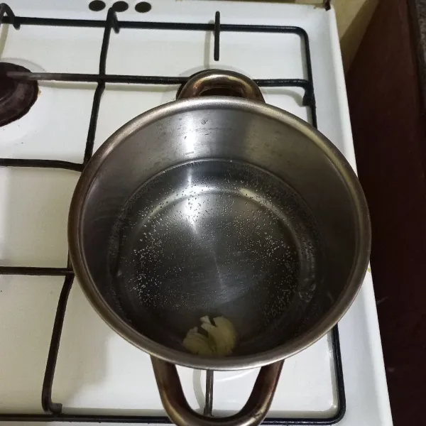 Rebus air dalam panci, masukkan bawang putih yang telah digeprek.
