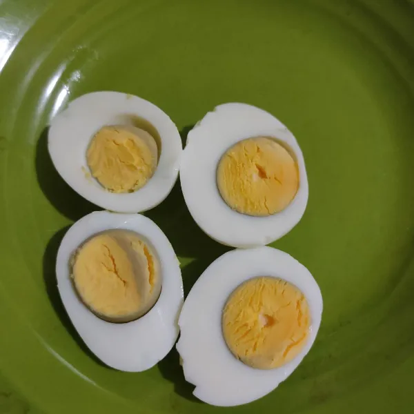 Rebus telur dan kupas, lalu potong jadi 2.