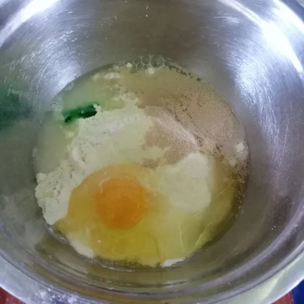 Dalam wadah masukkan terigu, gula pasir, susu bubuk, telur, ragi instan, air dan pasta pandan. Uleni sampai tercampur.