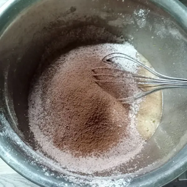 Masukkan campuran tepung terigu dan cokelat bubuk sambil diayak.